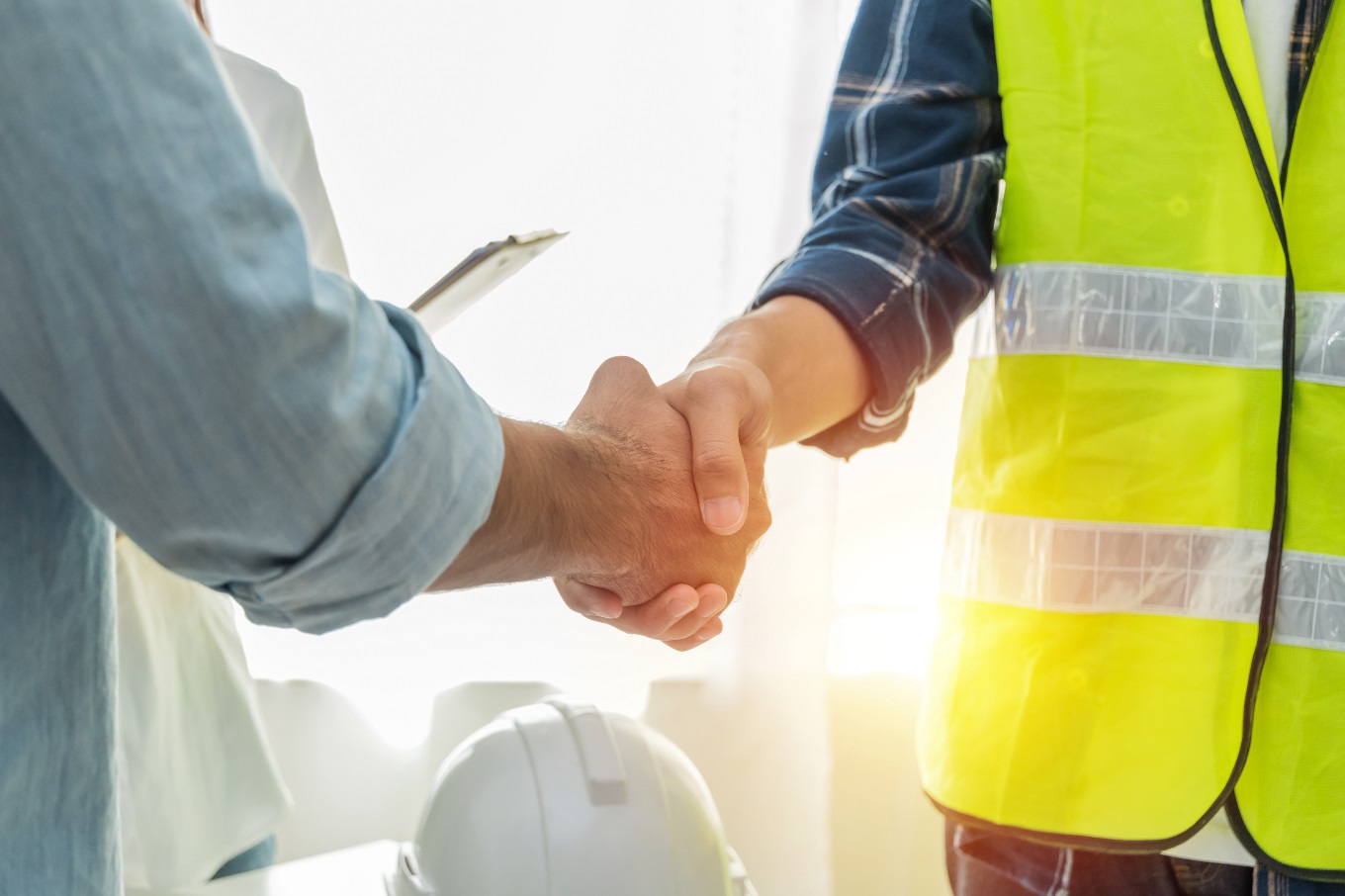 Contractor.-construction-worker-team-hands-shaking-after-plan-project-contract-on-workplace-desk-in-meeting-room-office-at-construction-site,-contractor,-engineering,-partnership,-construction-concept-1321891103